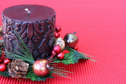Dark pattern candle with a small christmas wreath around it