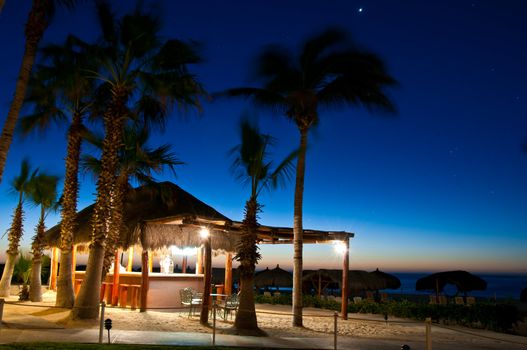 Empty grass hut bar on the beach in Mexico in the early morning.