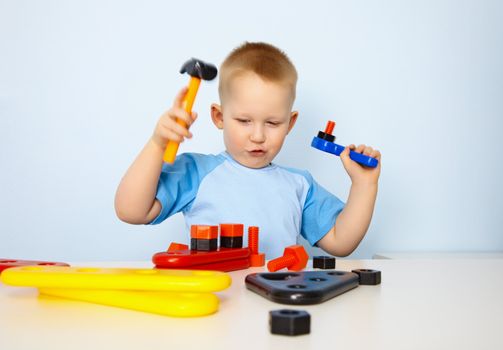 Little boy playing with a toy tool on blue background