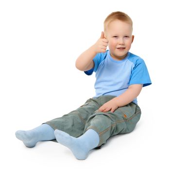 A little boy sits on a white background showing a gesture thumb up