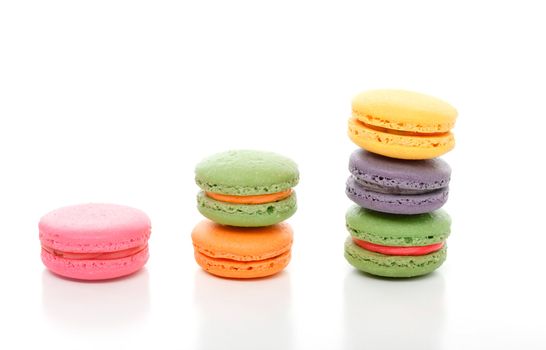 Decadent colourful French macaroons stacked on a white background.