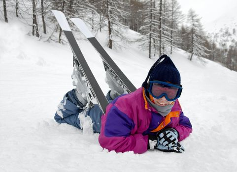 Young female skier resting on the snow