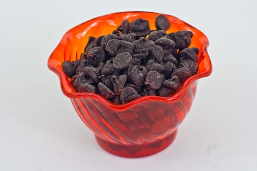 An orange cup with chocolate chips on a white background.