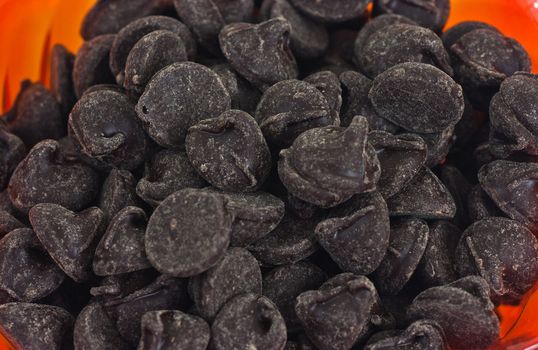 Chocolate chips in an orange bowl closeup.