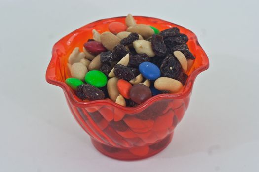 Orange cup with trail mix on a white background.