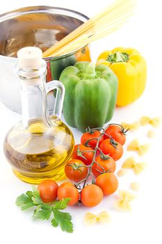 Pasta ingredients with olive oil, tomatoes, pepper and greens