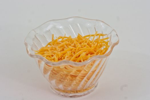 Cup of chedar cheese shredded in a pile.