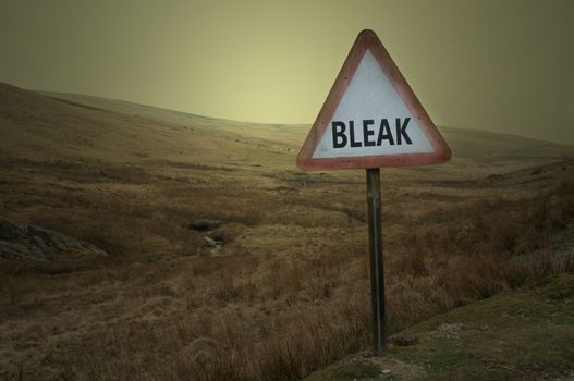 A weathered warning road sign with the word 'bleak' against a barren moorland landscape