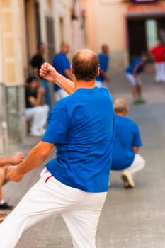 Traditional Spanish sportsman performing a powerful serve at a pelota match