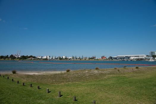 Orange oil boom snakelike across Tauranga harbour protects the beaches from contamination risk.