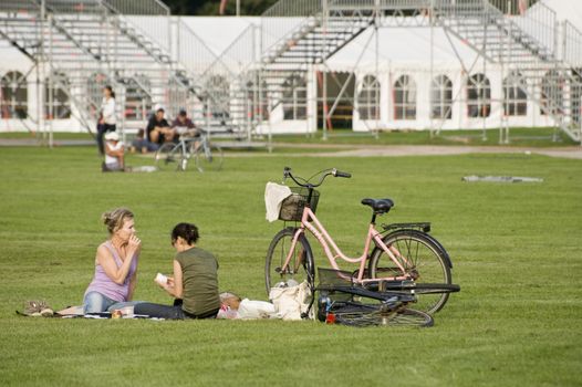 Two girls have a rest on city park of Copenhagen, Denmark