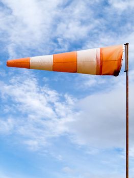 Red and white windsock wind filled partially clouded blue sky background