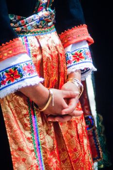 Orthodox Greek Easter Holiday: woman in traditional dress with folded hands on her red skirt.