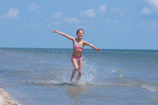 A happy child is running at the beach.