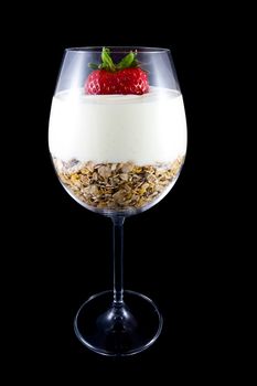 Picture of breakfast, musli and yogurt in a wine glass. With a strawberry on the top