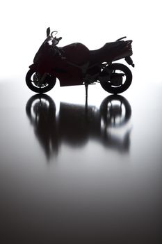 Silhouette of Street Motorcycle on Reflective Surface Against a White Background.