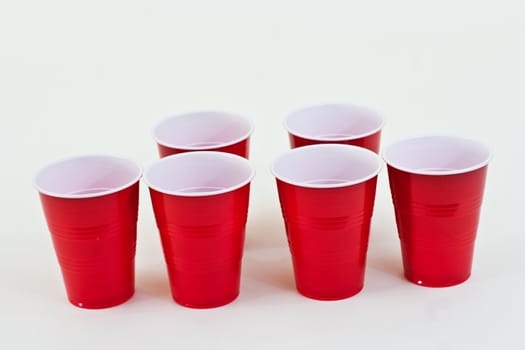 Red plastic cups spread out ready to be served on a white background.