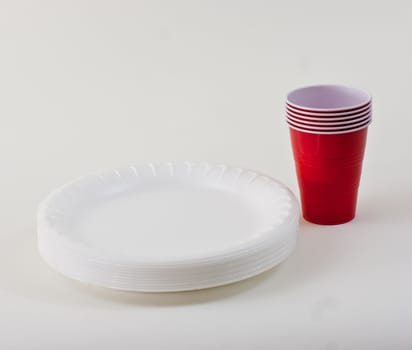 Red plastic cups and white styrofoam plates on a white background.