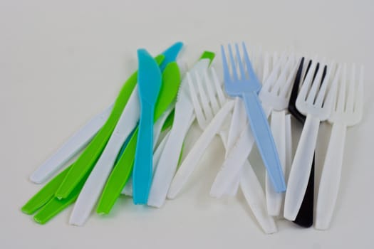 Blue,white,green, and black plastic forks on a white background.