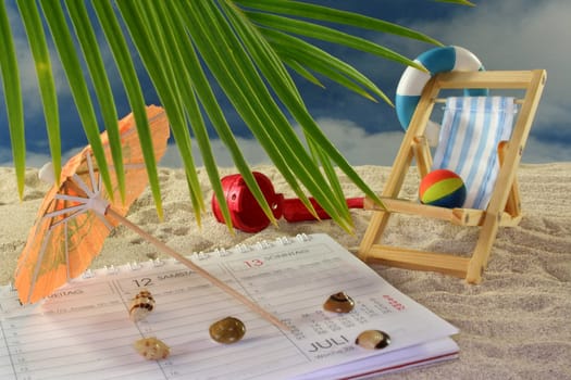 Calendar, lounge chair and umbrella on a sandy beach