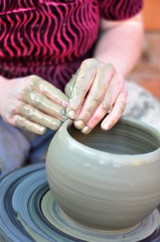 The hands of a potter creating an earthen jar 