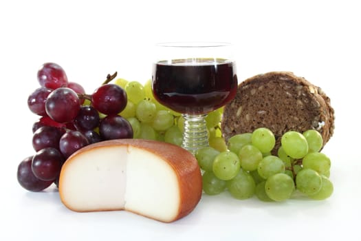 Cheese, bread and a glass of red wine on a white background
