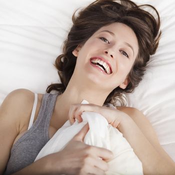 Beautiful and natural young girl on the bed laughing 