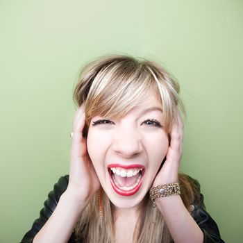 Young Caucasian woman screams with ears covered