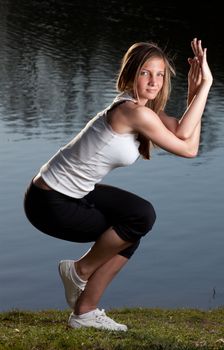 a young woman in a yoga stance in front of a lake