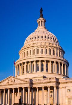 Capitol building in Washington DC illuminated early in the morning by the rising sun and giving a red/orange hue to the traditional scene