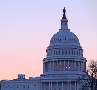 Brightly lit dawn sky behind the illuminated dome of the Capitol in Washington DC with the Statue of Freedom in the sunlight