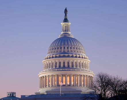 Brightly lit dawn sky behind the illuminated dome of the Capitol in Washington DC with the Statue of Freedom in the sunlight