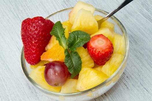 a fresh fruit salad with pineapple, orange, grape and strawberries