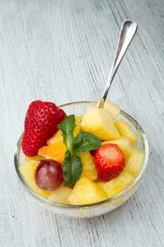 a fresh fruit salad with pineapple, orange, grape and strawberries