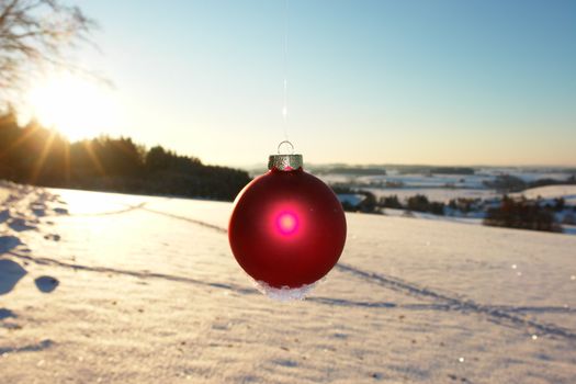 a red bauble in snowy winter landscape