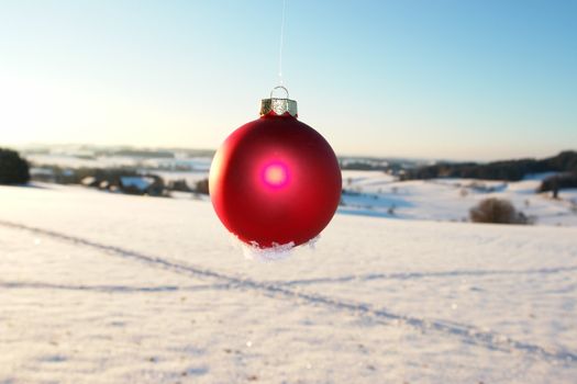 a red bauble in snowy winter landscape