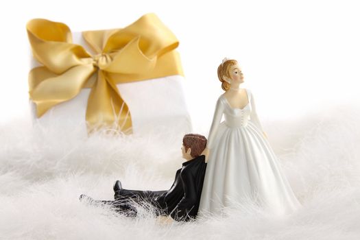 Wedding cake figurines with gold ribbon gift on white