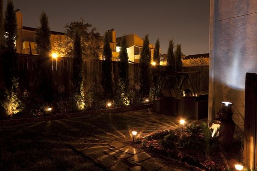 A patio garden or small backyard garden at night with pathway lights