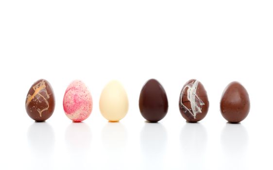 Six decadent luxury easter eggs.  Milk chocolatge with orange chips, white chocolate with strawberry crunch. pure white chocolate, pure dark chocolate, milk chocolate egg decorated with white and dark chocolate, and milk chocolate egg with toffee crunch pieces.