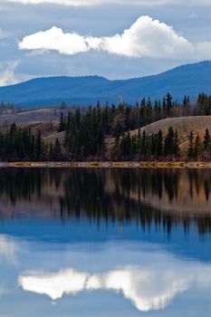 Power transmission line at calm small lake in late fall, Yukon Territory, Canada