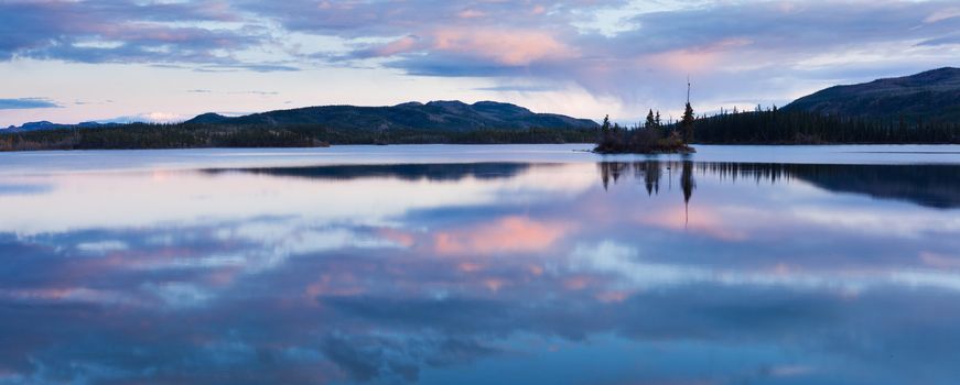 Calm lake reflecting sky at sunset, Twin Lakes, Yukon Territory, Canada.