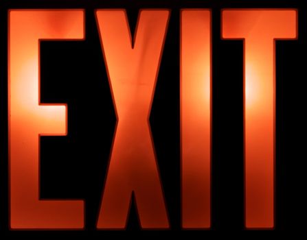 A red illuminated Exit sign isolated on a black background.