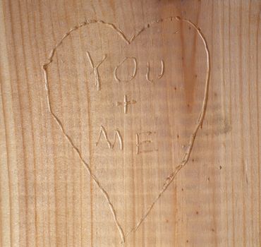 A heart with You and Me carved into wood