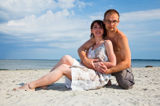 A young couple sitting together on the beach
