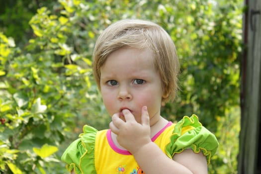 Cute little girl with blond hair in the garden
