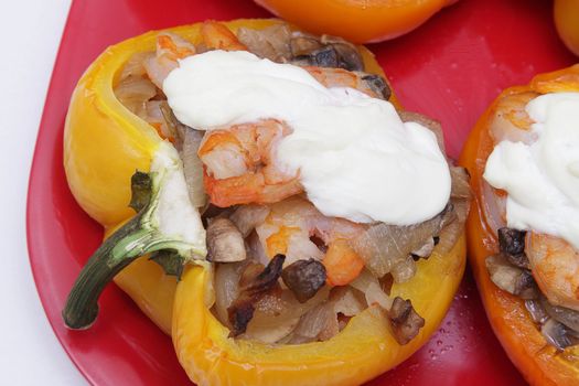 Stuffed pepper with shrimps, mushrooms and sour cream on red plate