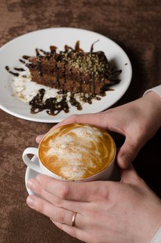 Closeup of female hands holding cup of Cappuccino