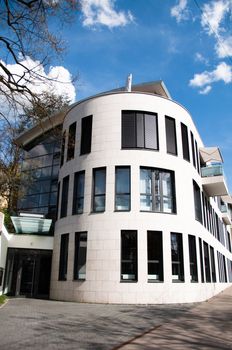 Modern white and gray architecture featuring square column glass panels and great cloudy blue sky