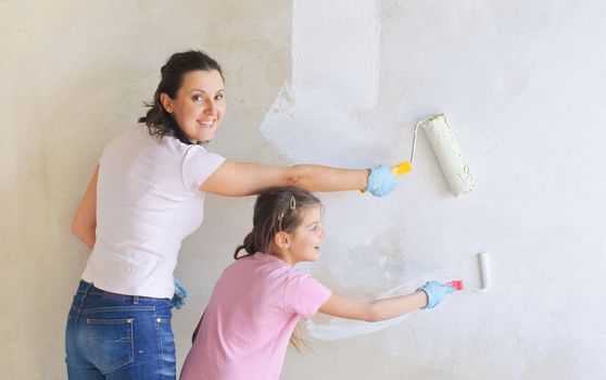 Friendly smiling Mother and douther painting a wall with roller