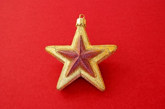 Christmas tree decoration. Golden star on red background.